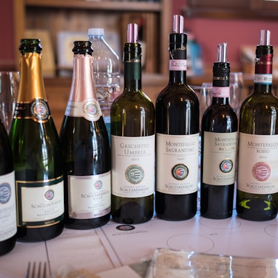 syv flasker vin på et bord