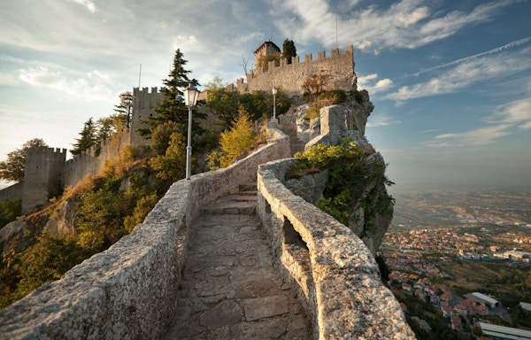 Steintrapp med mur som leder opp til flere slott på toppen av et fjell