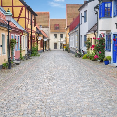 Brosteinsbelagt gate og fargerike hus i gamlebyen i Ystad, Sverige.