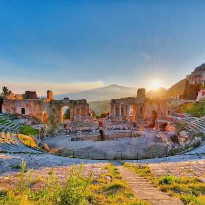 Det gamle Taormina-teateret med utbrudd fra vulkanen Etna ved solnedgang