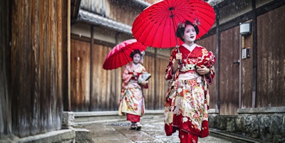 Maikos som går på en regnfull dag i gatene i Gion, Kyoto.
