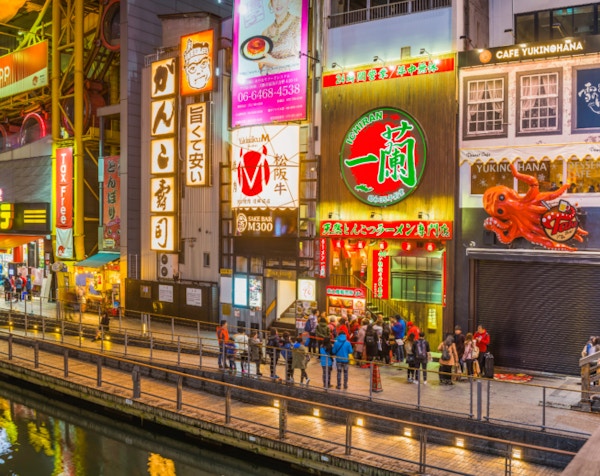 De fargerike neon reklametavlene som belyser restaurantene, barene og nattelivet i Dotonbori, gjenspeiler seg i den anonyme kanalen i hjertet av Osaka, Japans livlige andre by..