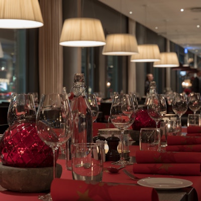 Bord dekket opp til fest og jul med rød bordpynt, tallerkner og glass