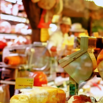 Vinduutsikt inn i en autentisk italiensk dagligvarebutikk med parmesanost og parmaskinke.