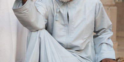 Senior omansk mann i tradisjonelle klær; dishdasha og kummah cap, ser på kameraet på markedet i Nizwa.
