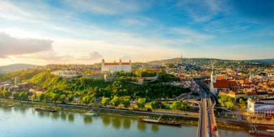 Bratislava flybilde med utsikt over gamlebyen med Saint-Martins katedral, slottshøyden og Donau-elven ved solnedgangen i Slovakia. Vidvinkel med kopieringsplass