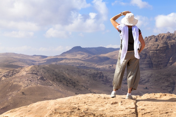 Kvinne beundrer utsikten over den jordanske ørkenen mens hun vandrer i Petra.