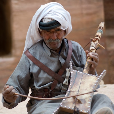 Beduin eldstemann som spiller strenginstrument på det eldgamle stedet for Petra i Jordan