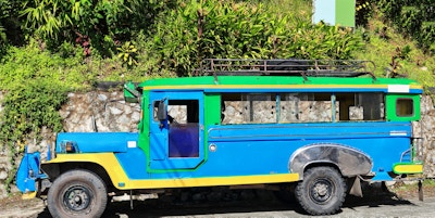Filippinsk grønn-blå-gul dyipni-jeepney bil. Offentlig transport i Banaue by, opprinnelig laget av amerikanske militære jeeper som var igjen fra WW.II lokalt endret - nå fra japansk overskudd. Filippinene.