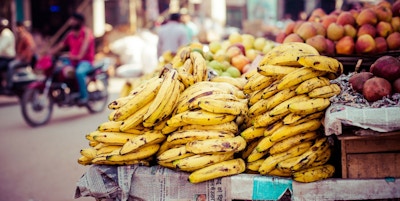 Bananer ligger oppå et avispapir på et marked ved ei trafikkert gate