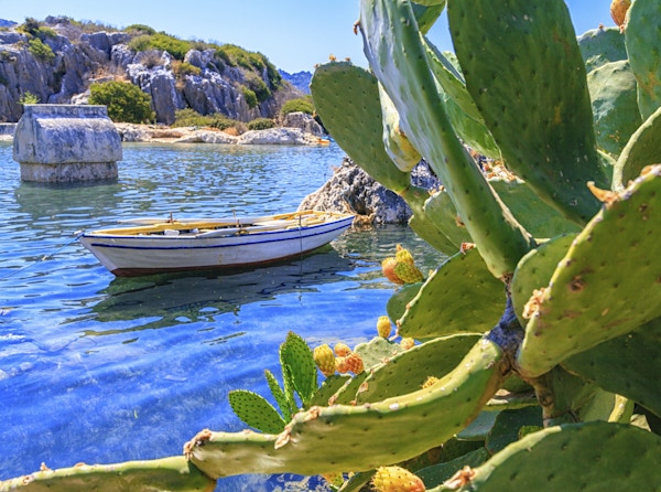 Historsisk minner om en sunken by på kysten av Tyrkia, vann og en båt vises også