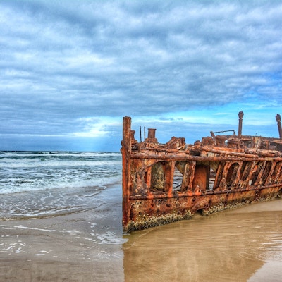 Et rustent skipsvrak i vannkanten på stranden på Fraser Island
