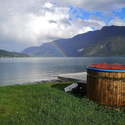 Badestamp ved fjorden med regnbue i bakgrunnen.