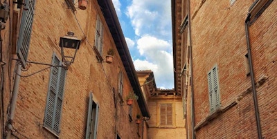 En trang bygate i Fano med blå himmel og skyer