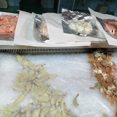 Fisk og skalldyr på fiskemarkedet ligger på is og utvalgte typer er klare til å pakkes inn for kunden