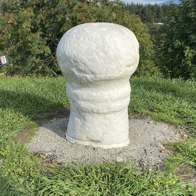 Hvit stein formet som et fallos-symbol ute i en park