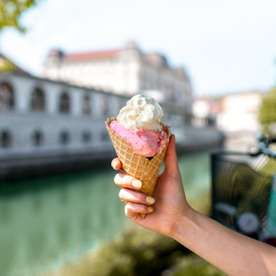 Kvinnelig hånd som holder iskrem på vann chanal og sykkel på bakgrunnen i Ljubljana city. Slovensk gatemat