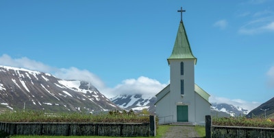 Hvit kirke foran snøkledde fjell