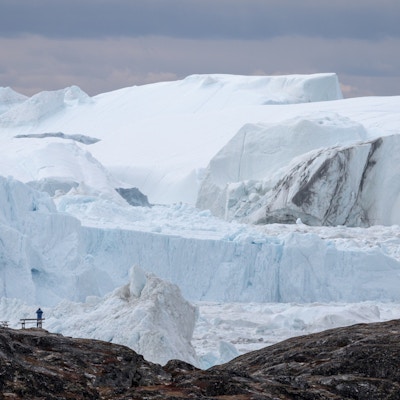 Mennesker som ser på store, blå isfjell på havet utenfor Grønland