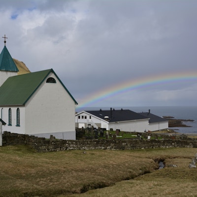 Regnbuen ender i kirkeveggen i den hvite, lille kiken i landsbyen Gjògv på Færøyene