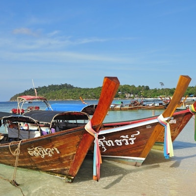 Trebåter med fargerike bånd festet rundt fronten ligger på stranden