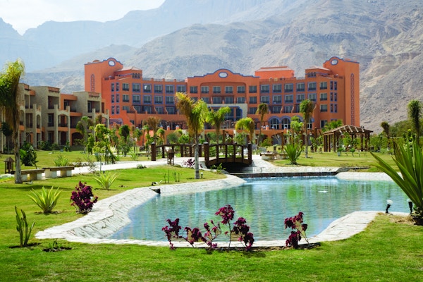 Hotellbygning med grøntområde og beplantning og ørken i bakgrunn