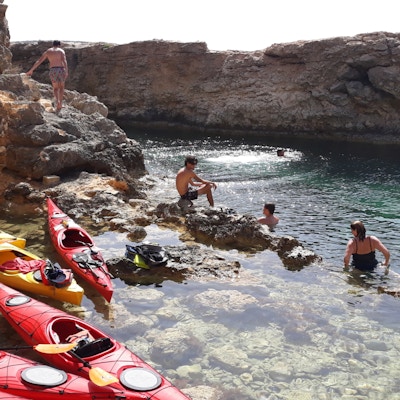 En gruppe mennesker bader i havet mens kajakkene ligger parkert i en lagune
