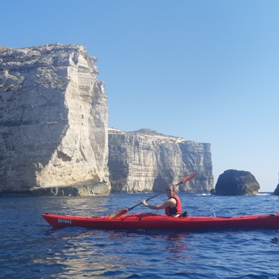 En padler foran den dramatiske kystlinjen på Gozo