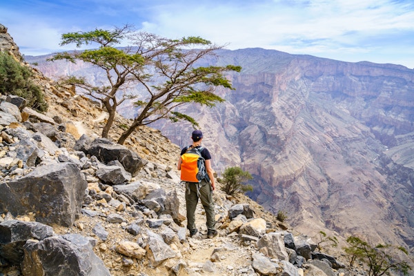 En turgåer nyter utsikten over canyonen i Jebel Shams-fjellet i Oman