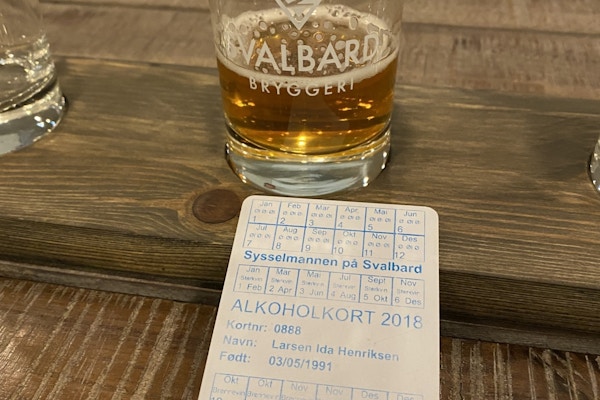 Ølglass med innhold og et alkoholkort ved siden av