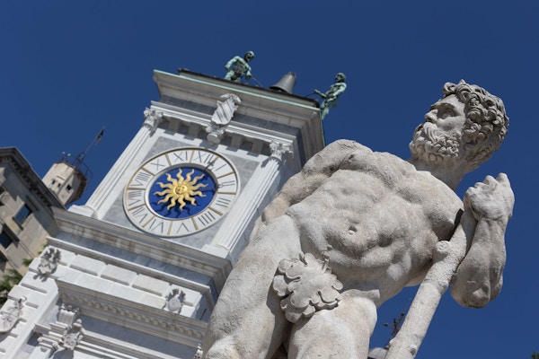Det gamle klokketårnet og en statue på Piazza Libertá i Udine