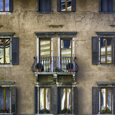 En fargerik tradisjonell italiensk fasade med gamle persienner og refleksjoner, Udine. Italiensk antik arkitekturstil