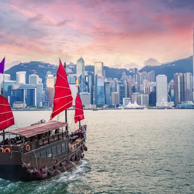 Seilbåt seiler inn til Hong Kong Victoria Harbour ved solnedgang