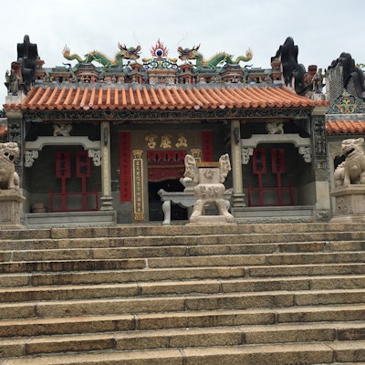 Et tempel med trapp opp og fargerike figurer av blant annet drager på taket