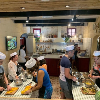 En gruppe mennesker lager mat på et kjøkken på kokkekurs på Malta