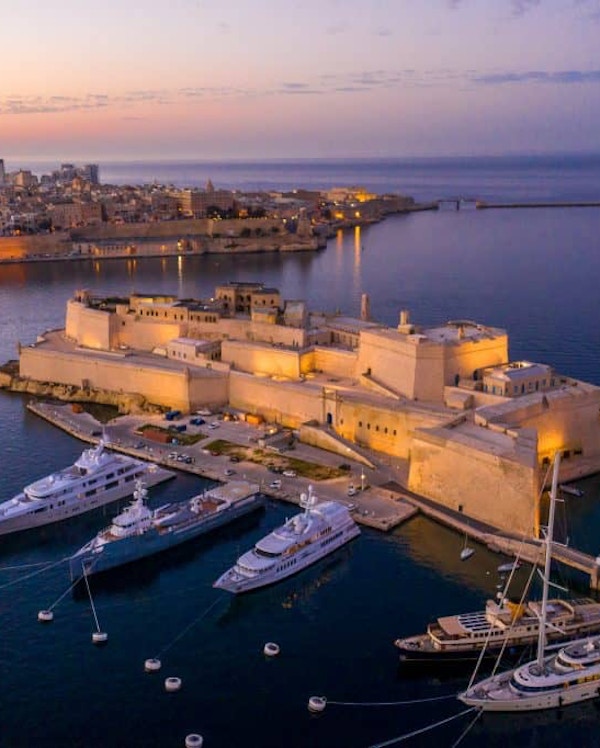 Havnen i Birgu sett ovenfra med store yachter til kai og  utsikt mot Valletta