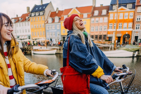 Bilde av to unge kvinner som sykler og har det gøy mens de oppdager den nye byen sammen.