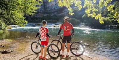 To syklister som står med ryggen til og ser utover vann og fossefall