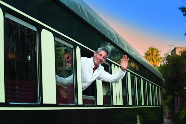 Mann som vinker ut av et vindu på Rovos Rail
