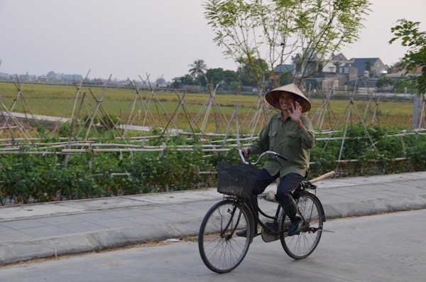 Mann på sykkel med asiatisk hatt.