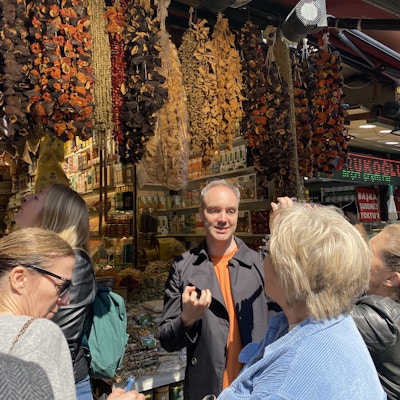Kvinner står foran krydderbasarene i Istanbul og hører en mann fortelle