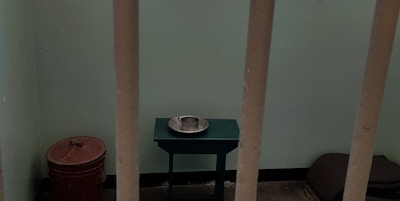 Enkel fengselscelle fra fortiden med lite bord og en krakk