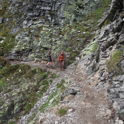 Fire personer vandrer på en smal sti på vei ned fra Bitihorn