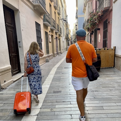 To personer går nedover et gate med en trillebad i oransje