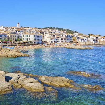 Calella de Palafrugell, katalanske kystnære landemerke i juli. Mange mennesker i den steinete stranden med parasoller.