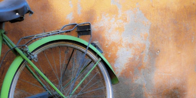 Lysegrønn retro-sykkel som lener seg mot en flekkete gammel oransje vegg