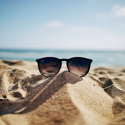 Sand, hav og et par solbriller plassert ut