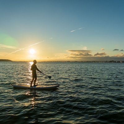 Mann på SUP, padlebrett i solnedgang