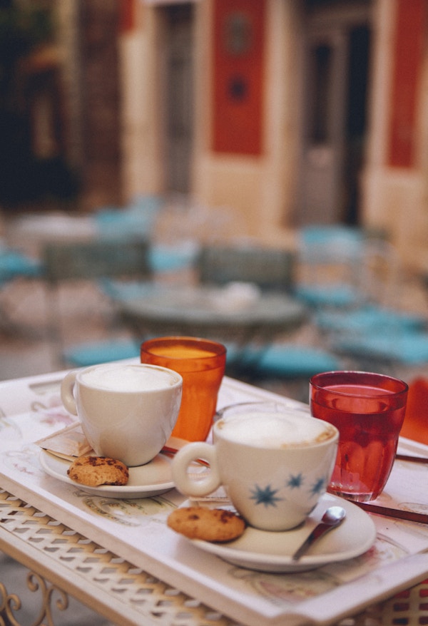 Liten gatekafé i gamlebyen i Rovigno, Kroatia. Italiensk espresso serveres med hjemmelagede cookies og et glass vann på en varm sommerdag på et vintage trebord.