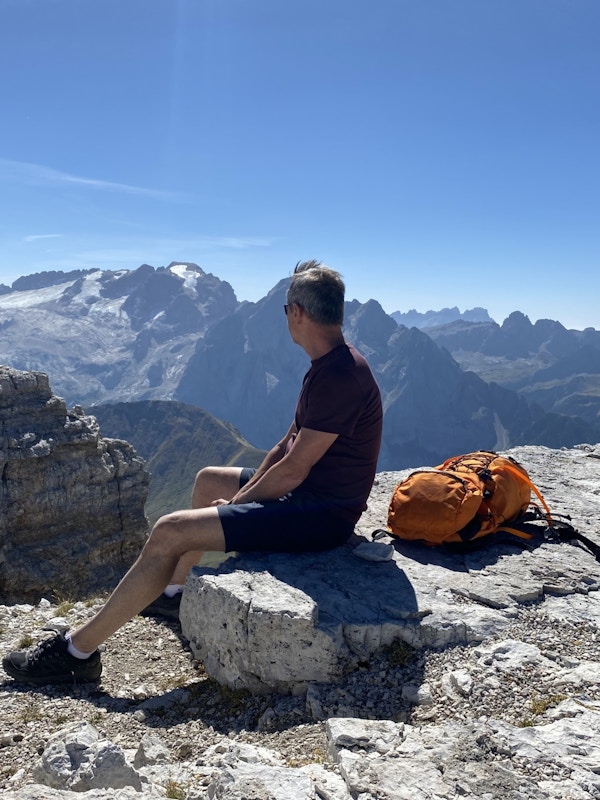Mann sitter med ryggen til og ser mot utsikt på fjelltur